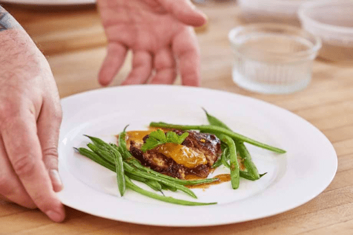 Promotional image of Upside Foods' lab-cultivated meat alternative product arranged on a dinner plate with a string-bean garnish.