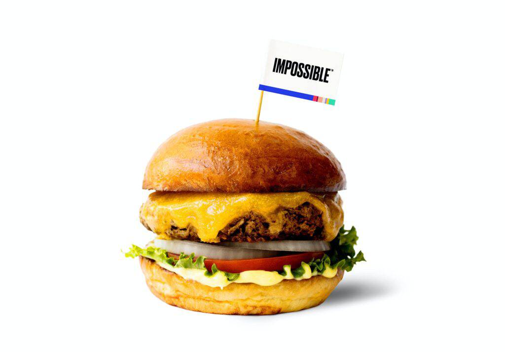 Promotional image of an Impossible Foods-brand burger patty on an open-faced roll.